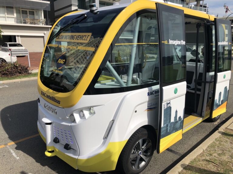 Picture of intellibus electric autonomous vehicle, white and yellow. With open doors.